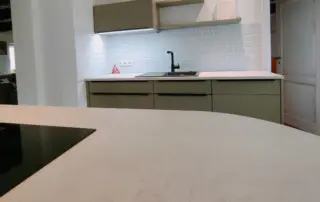 Küchenstudio Moderne Küche mit hellen Arbeitsplatten, olivfarbenen Schränken, weißem Subway-Kachelboden, schwarzem Wasserhahn und einem Induktionskochfeld im Vordergrund. Küchenstudio Moderne Küche mit hellen Arbeitsplatten, olivfarbenen Schränken, weißem Subway-Kachelboden, schwarzem Wasserhahn und einem Induktionskochfeld im Vordergrund.