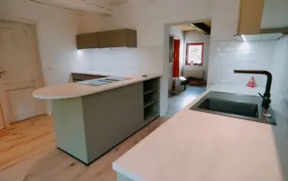 Küchenstudio Moderne Küche mit hellen Arbeitsplatten, Insel mit eingebautem Herd, Unterschrankbeleuchtung, weißer Subway-Fliesenrückwand und Holzfußboden. Küchenstudio Moderne Küche mit hellen Arbeitsplatten, Insel mit eingebautem Herd, Unterschrankbeleuchtung, weißer Subway-Fliesenrückwand und Holzfußboden.