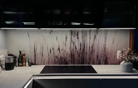 Küchenstudio Moderne Küche mit Kochfeld, hellgrauer Arbeitsplatte, Olivenölen und einer Küchenrückwand mit einem von der Natur inspirierten Grasmuster. In der Ecke steht eine Vase mit Trockenblumen. Küchenstudio Moderne Küche mit Kochfeld, hellgrauer Arbeitsplatte, Olivenölen und einer Küchenrückwand mit einem von der Natur inspirierten Grasmuster. In der Ecke steht eine Vase mit Trockenblumen.