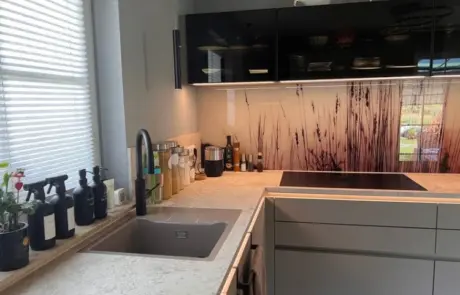 Küchenstudio Moderne Küche mit Spüle, Wasserhahn, Seifenflaschen und Kräutertöpfen auf der Fensterbank; Induktionskochfeld mit Schränken und einer Fliesenwand im Naturdesign. Küchenstudio Moderne Küche mit Spüle, Wasserhahn, Seifenflaschen und Kräutertöpfen auf der Fensterbank; Induktionskochfeld mit Schränken und einer Fliesenwand im Naturdesign.